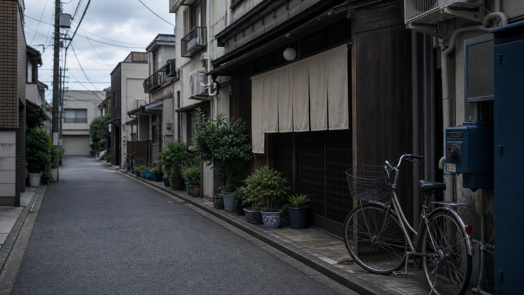 架空の浅草に似た裏通り。曇り空の下、古い家並み、白い暖簾、自転車、鉢植えが静かに並んでいる。